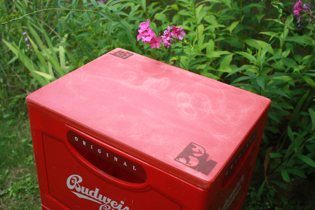 Bankmeister Holzauflage Rot auf Getränkekiste im Garten mit Blume